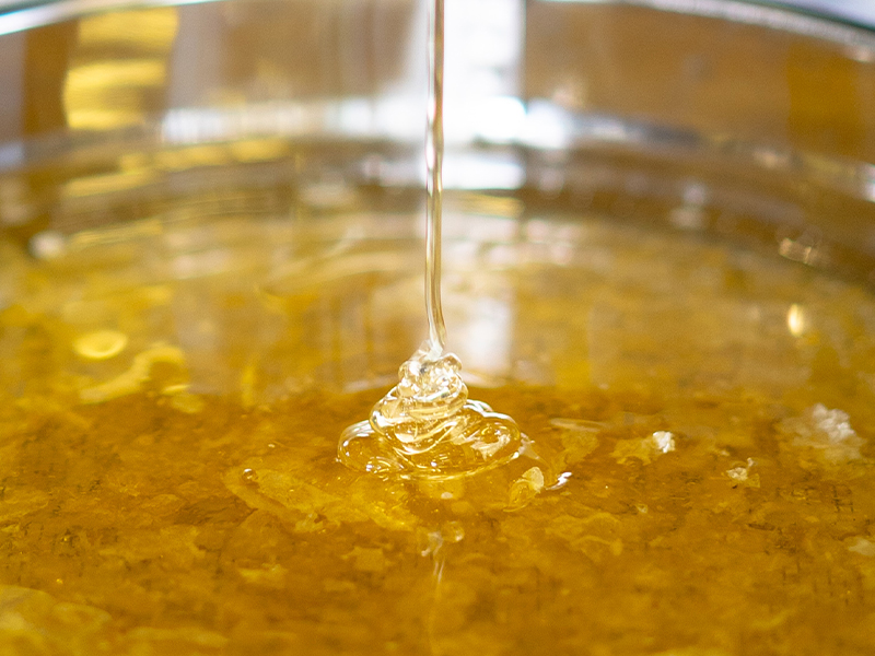 生はちみつが糸を引くようにゆっくり流れる様子のアップ写真