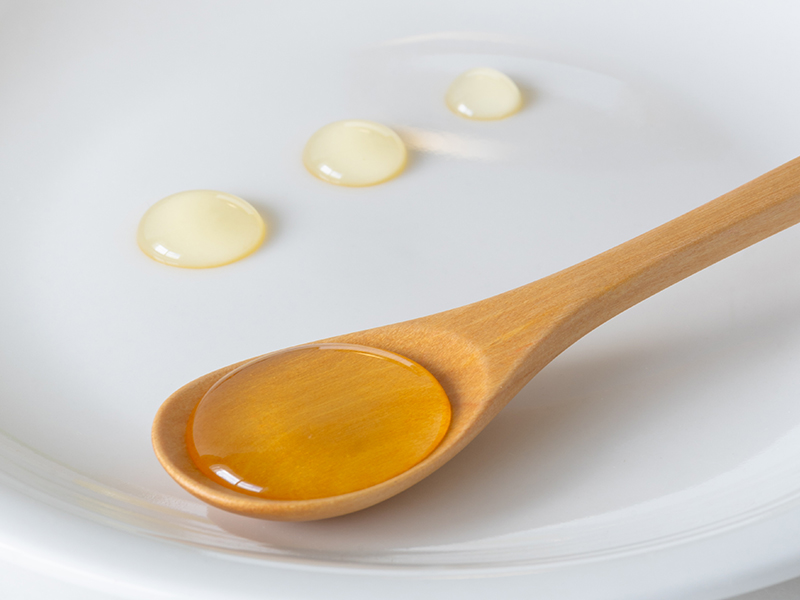 スプーンにすくった生はちみつと、皿の上に置いたはちみつの三段階の状態