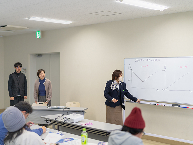 東北銀行の担当者が、ホワイトボードを使いながらNISAやiDeCoなどの資産形成について解説している様子