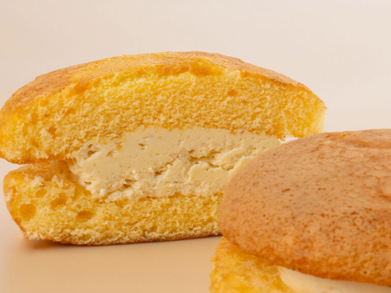 ハニーチーズブッセの柔らかな焼き生地と、たっぷり詰まったなめらかなチーズクリームの断面アップ